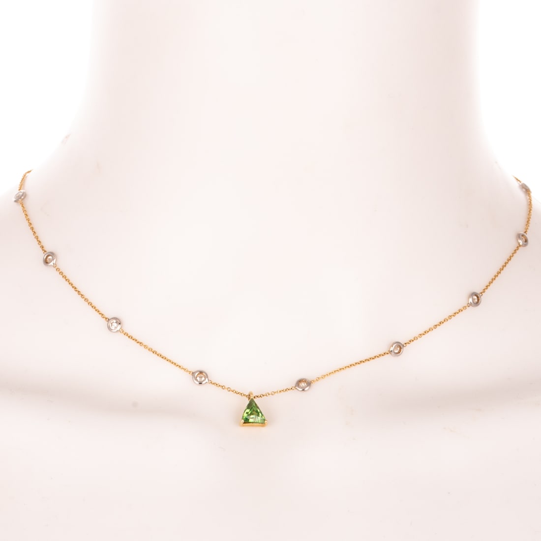 A Diamond Station & Tsavorite Garnet Necklace in 18K: 18K yellow gold Italian cable link necklace featuring 14 bezel set round diamond stations weighing approx. 1.00 ctw with a prong set trilliant cut tsavorite garnet measuring 6.5 x 6 mm dangling in the