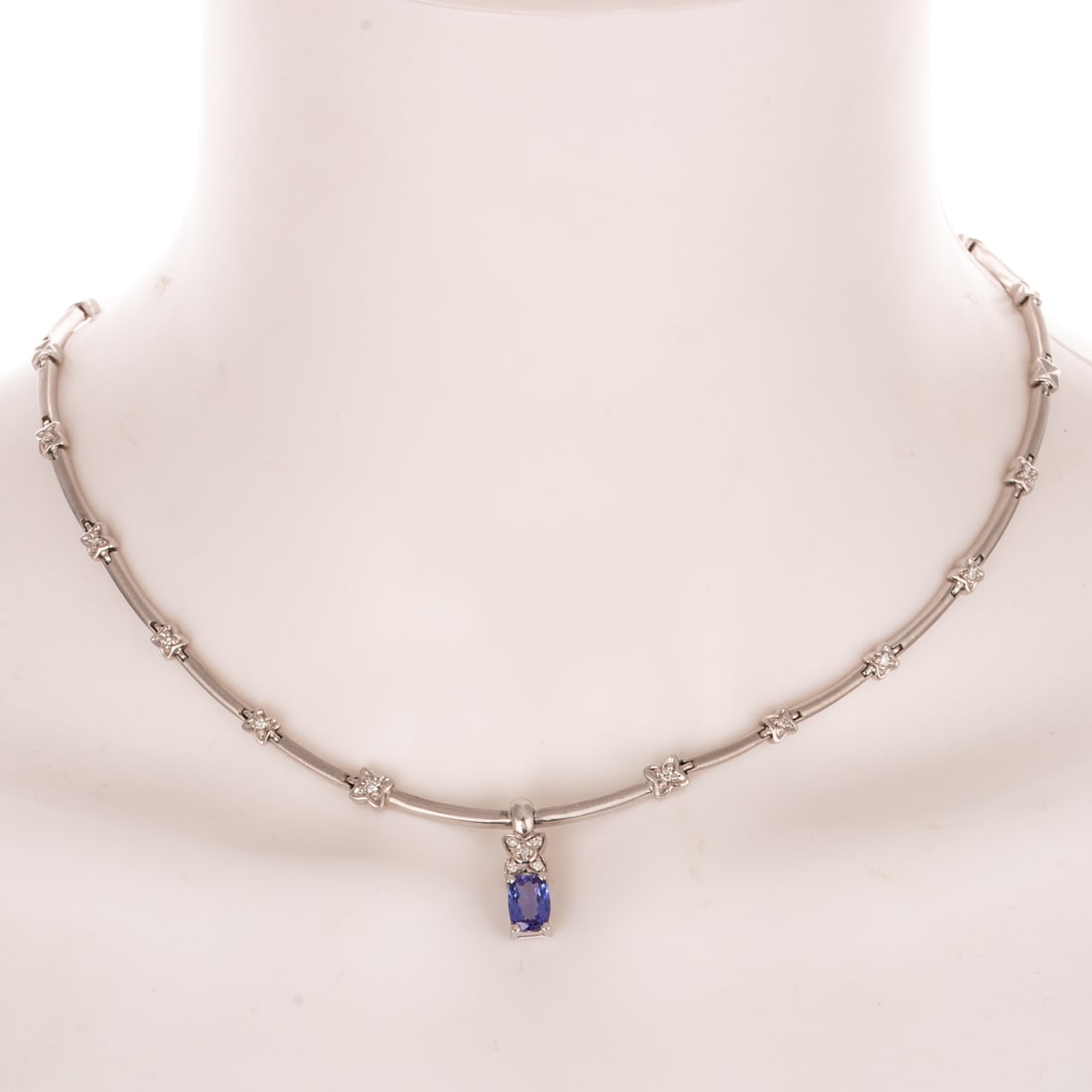A Tanzanite & Diamond Necklace in 14K: 14K white gold necklace featuring a cushion cut tanzanite weighing approx. 1.20 cts set in a pendant dangling from line necklace designed with matte finish links alternating with evenly spaced diamond