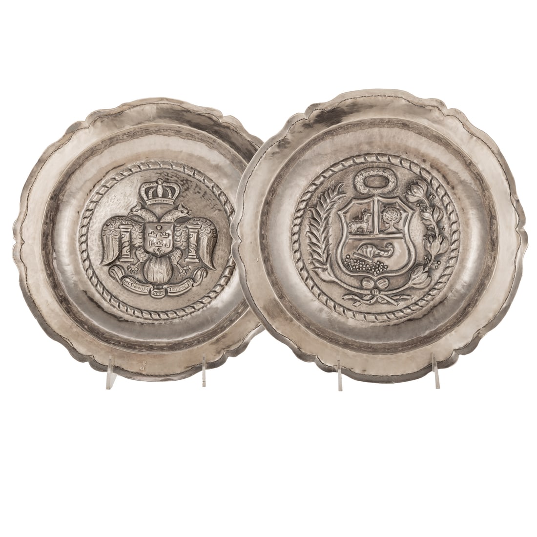 Two Peruvian Sterling Repousse Chargers: Each stamped EV/925/Peru/Mano. Circular, with serpentine rim, each hand-decorated, one featuring the Peruvian coat of arms, one with the 18th century Lima coat of arms, 11 1/2 in. Diam., 24.7 ozt.