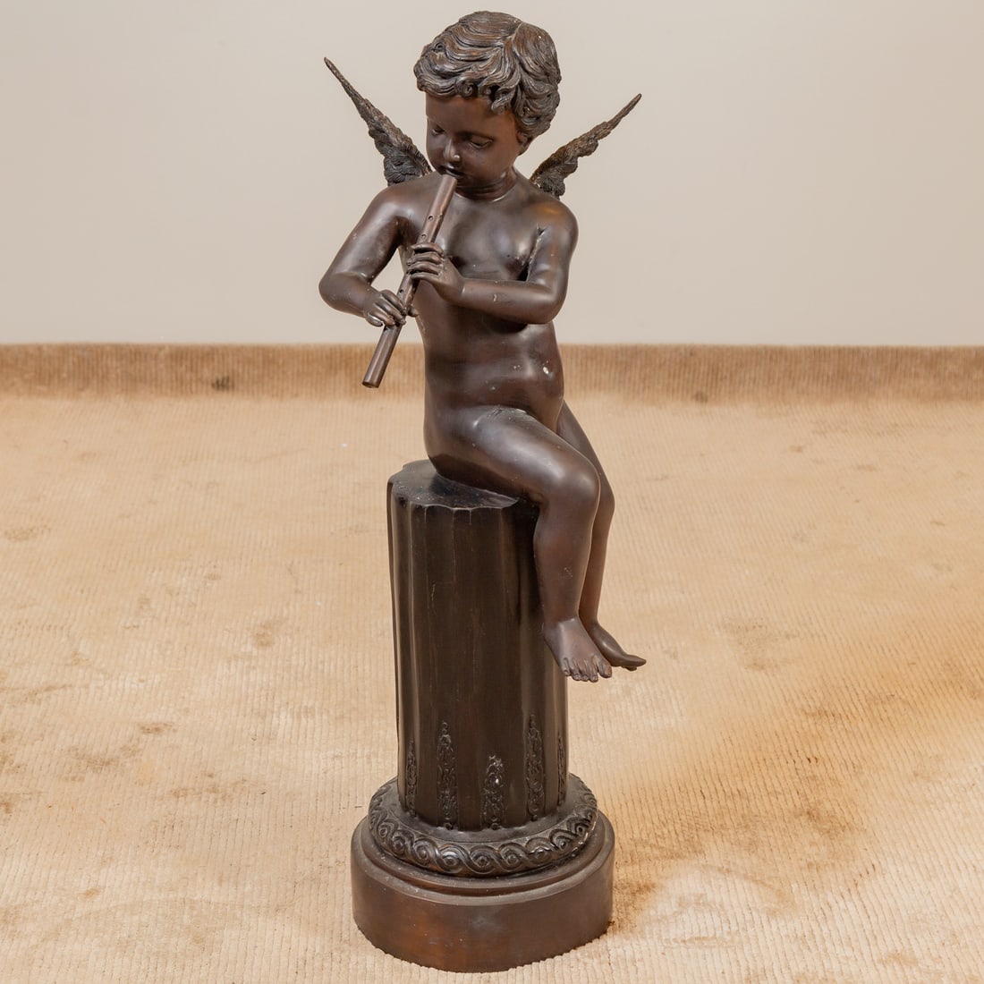 After Giuseppe D'ASTE. Putto Playing Pipe, bronze: Joseph Giuseppe D'ASTE (1881-1945) A patinated bronze of a putto seated on a partial column playing a pipe, signed "J. DASTE" on column, 42 1/2 in. H, 16 in. Diam.