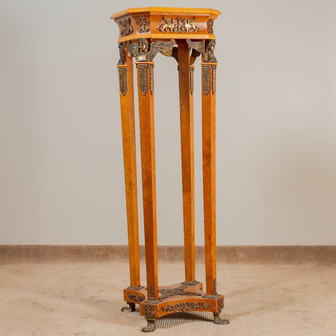 Egyptian Revival Walnut Pedestal: In the Napoleon I manner, octagonal figured walnut top with gilt metal applied decoration on four tapered legs connected at the base by a solid shaped stretcher on herm feet, 55 1/2 in. H, 17 in. Sq.