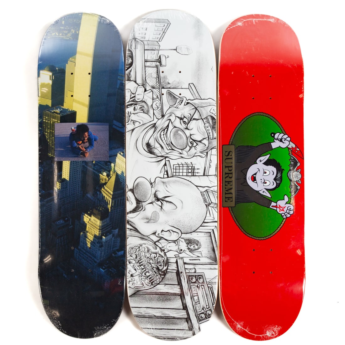 Three Supreme Skateboard Decks: Including: a Supreme "Mister Cartoon" skateboard deck in Chicano-style clown motifs, 2024 collection, artwork by Mister Cartoon (Mark Machado); the red Supreme "Vampire Boy" skateboard deck,