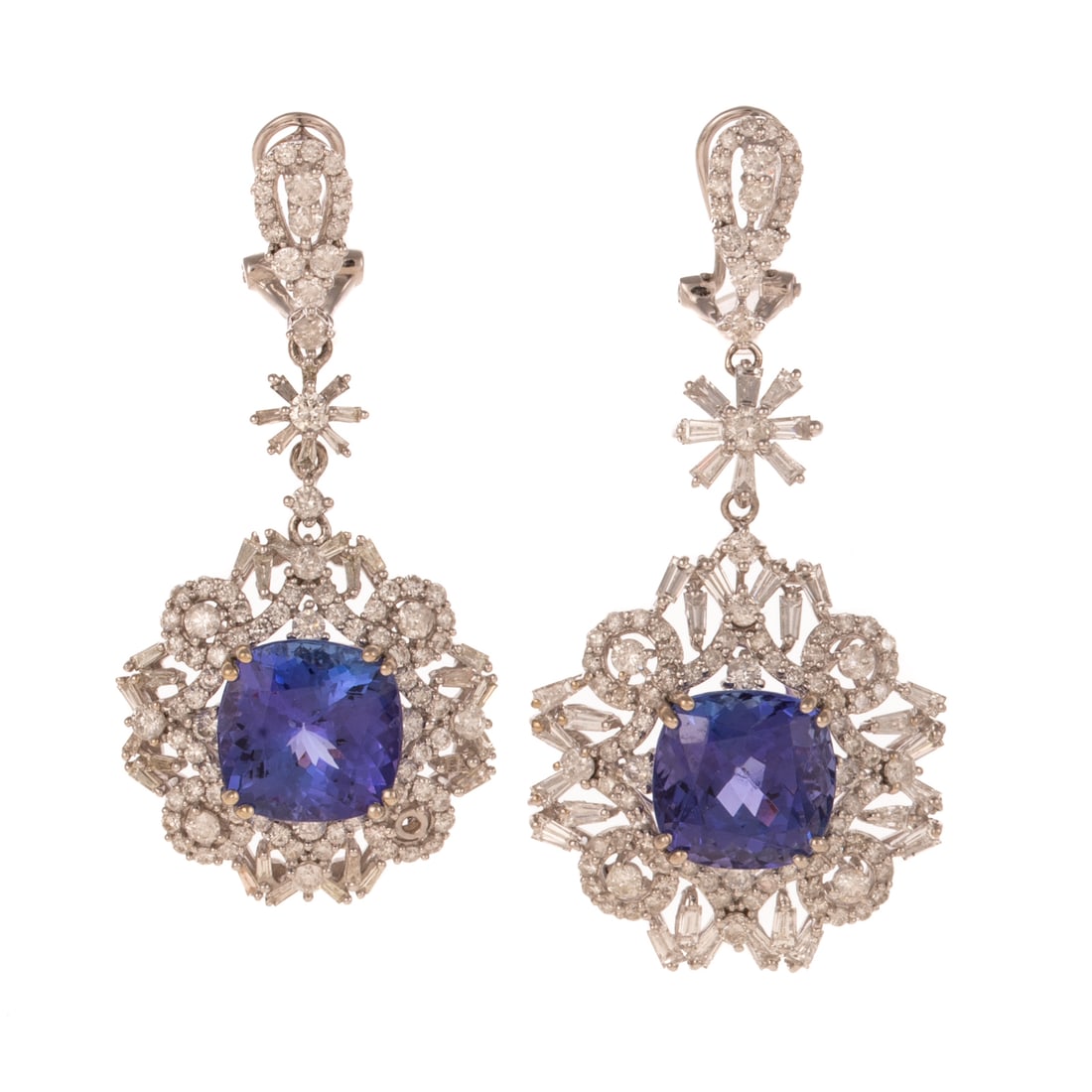 A Near Pair of Tanzanite & Diamond Earrings in 14K: 14K white gold earrings by Orianne featuring cushion cut tanzanites weighing approx. 12.00 ctw prong set in the center of similarly designed wreaths of baguette and round diamonds prong set dangling b