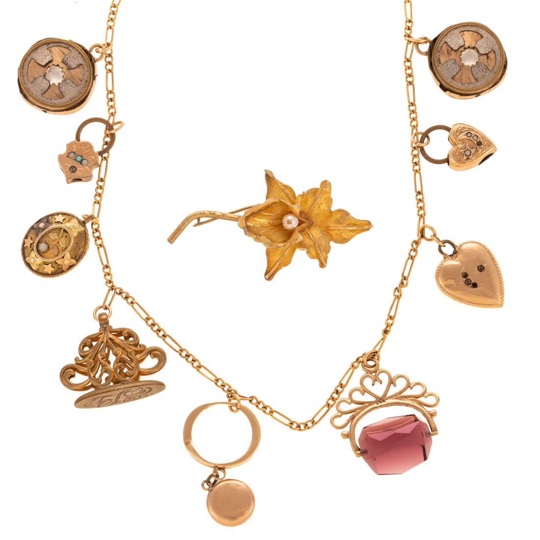 A Vintage Charm Necklace in Gold: Gold filled figaro link necklace featuring nine charms including two 10K and copper wheels, two 14K heart charms, a 9K purple stone fob, 14K ring and circle charm, a gold filled fob, a 10K flower egg 