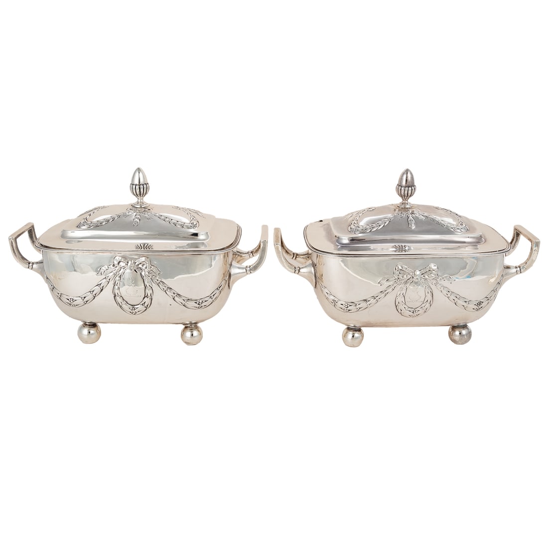 A Pair of George III Silver Armorial Sauce Tureens: John Emes, London, 1807. Rectangular, with rounded corners, decorated with repousse garlands, the wreath with a chased armorial crest depicting a crescent over an escallop, the lift-off cover with aco