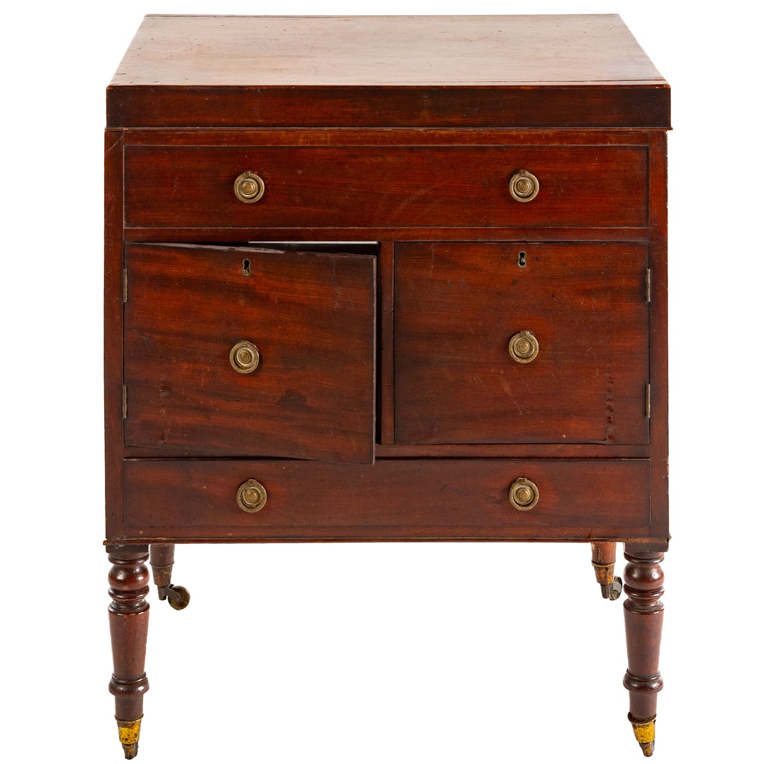 Sheraton Style Beau Brummel Dressing Chest: Hinged top concealing a fitted interior over a false drawer and a pair of cabinet doors above a single drawer, supported on turned and castered feet, 34 in. H, 28 in. W, 21 in. D Provenance: From a