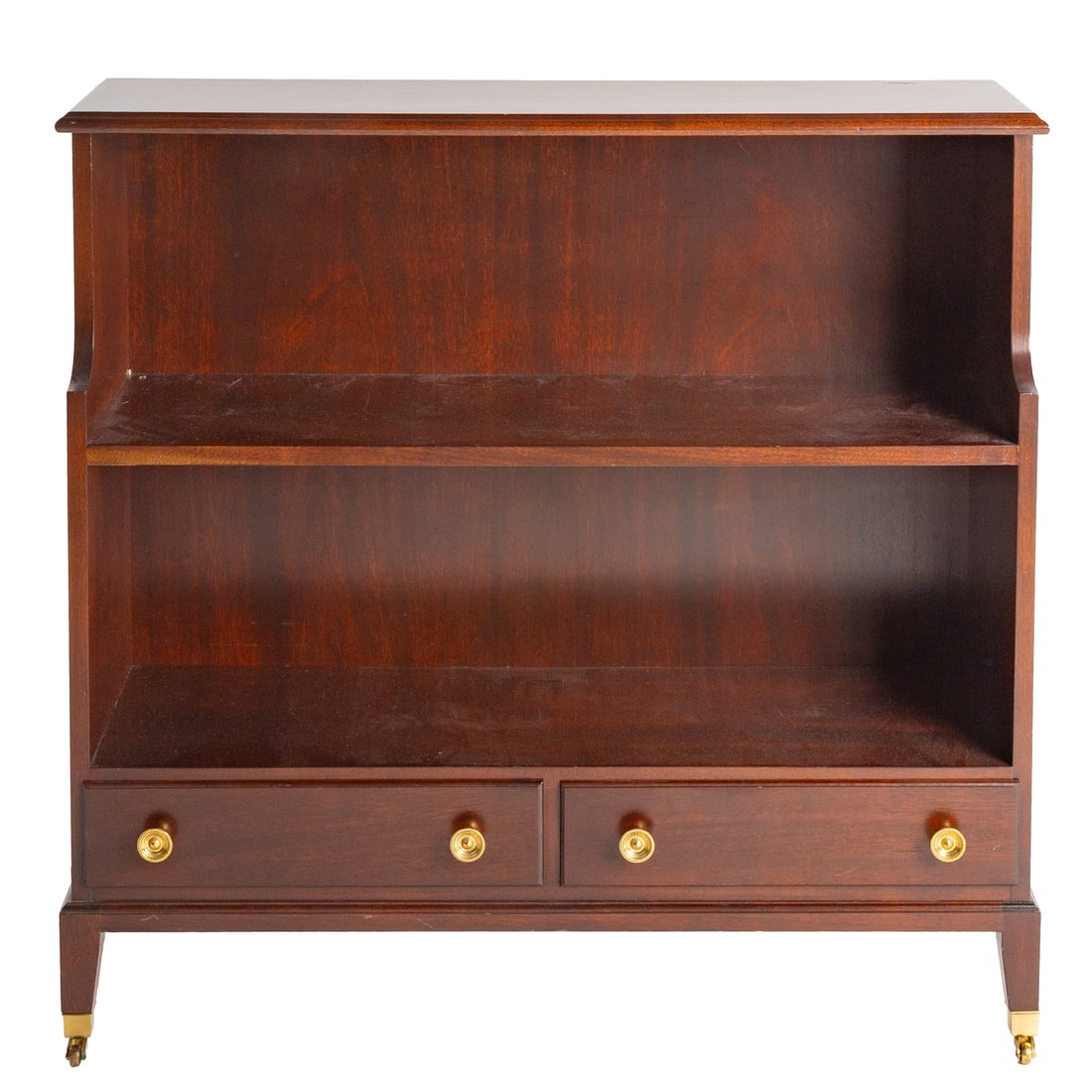 Georgian Style Mahogany Bookcase: Two-shelf movable bookcase with two drawers, brass bail pulls on the sides, tapered legs ending in brass caps and casters, 34 1/2 in. H, 36 in. W, 12 in. D Provenance: From a private Delaware