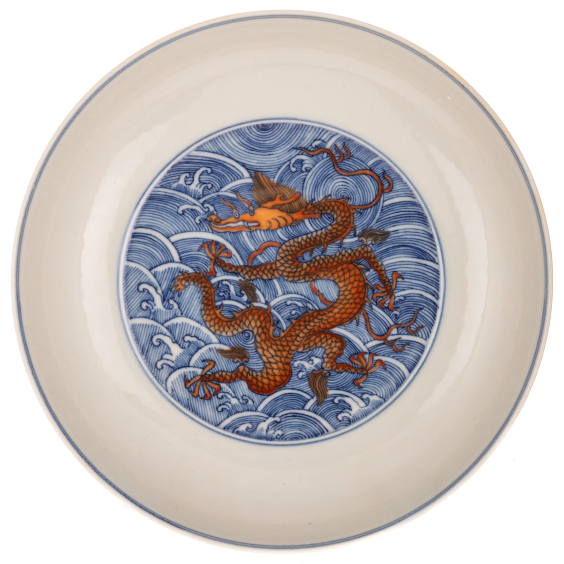A Chinese Porcelain Dragon Dish: An iron red and underglaze blue Chinese porcelain dragon dish, central interior decorated with an iron red dragon amid swirling waves in underglaze blue, the exterior decorated with nine dragons