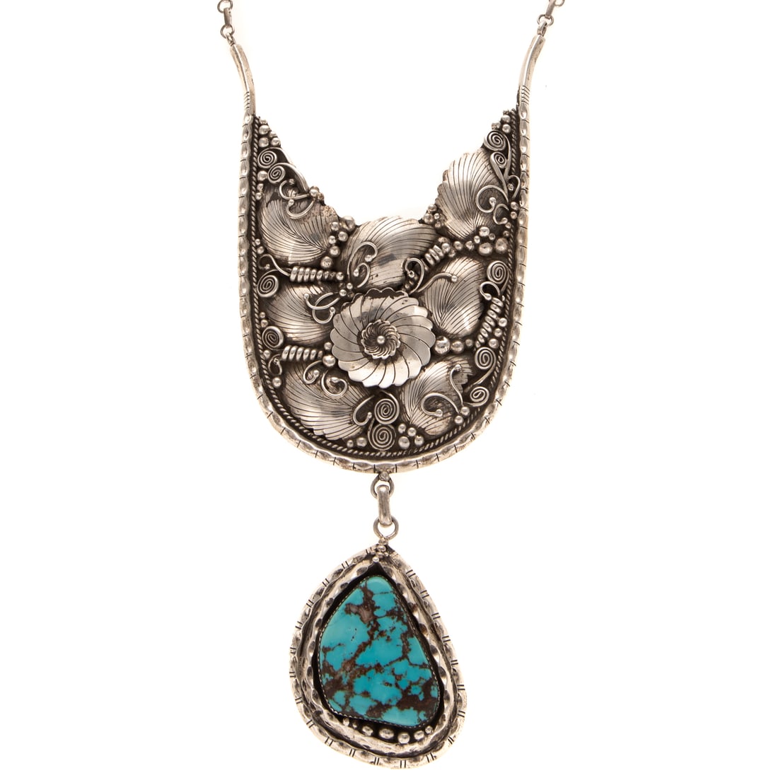 A Rose Castillo Turquoise Bib Necklace in Sterling Silver: c. 1980s, Sterling silver bib necklace by Navajo artist Rose Castillo featuring a large bib of silver with a central flowers amid foliage with wire and bead details, suspending a pendant of Kingman tu