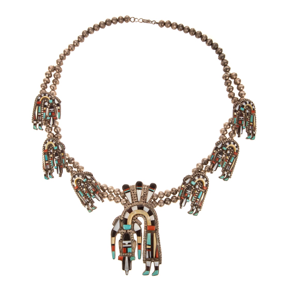 A Signed Zuni Rainbow Man Necklace in Sterling Silver: Sterling silver Rainbow Man squash blossom style necklace by Zuni artist Oliver & Angela Cellicion featuring stone inlay including turquoise, coral, jet, and Mother of Pearl, hook clasp, 26 in. L, sig