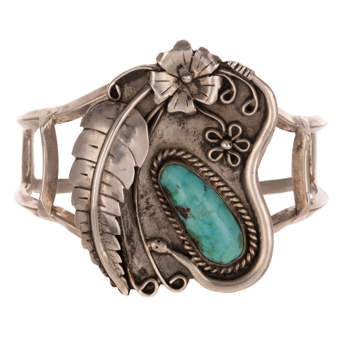 A Signed Navajo Turquoise Cuff in Sterling Silver: Sterling silver cuff bracelet by Navajo artist featuring a bezel set freeform turquoise with feather and flower accents, signed "DM," 2 1/2 interior Diam., 47.2 grams Provenance: From a private collec