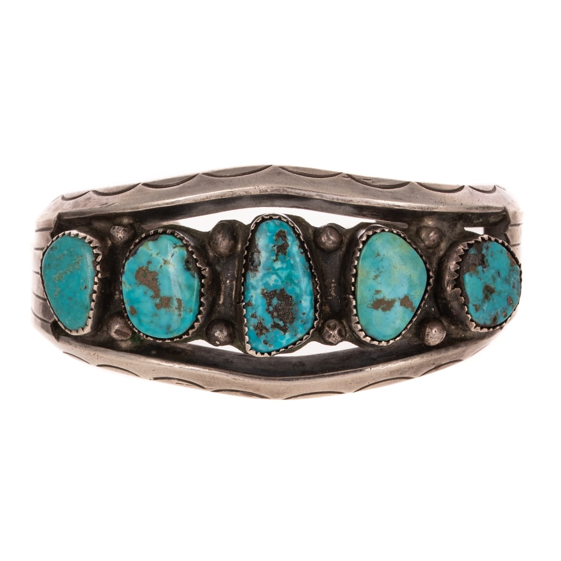 A Navajo Turquoise Cuff Bracelet in Sterling Silver: Sterling silver wide cuff bracelet featuring free form turquoise bezel set in the center and engraved outer edges, 1 1/4 in. W, 2 1/2 interior Diam., 74.3 grams Provenance: From a private collection f
