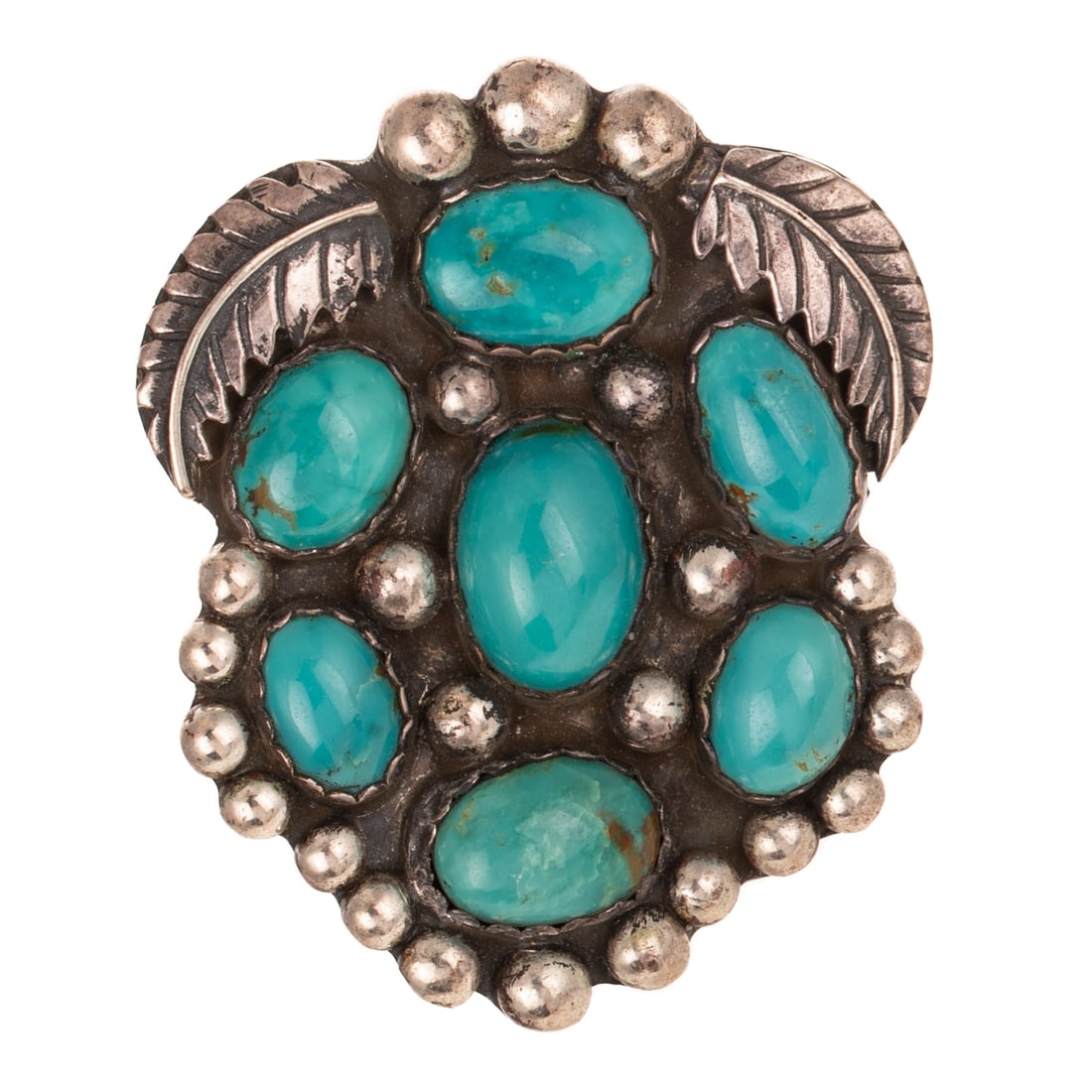 A Signed Vintage Turquoise Cluster Brooch in Sterling Silver: Sterling silver brooch possibly made by Navajo designer Glenn and Irene Sandoval featuring high quality turquoise set in oval cluster with leaf accents at the top, 2 1/4 in. L, signed, 33.6 grams Prov