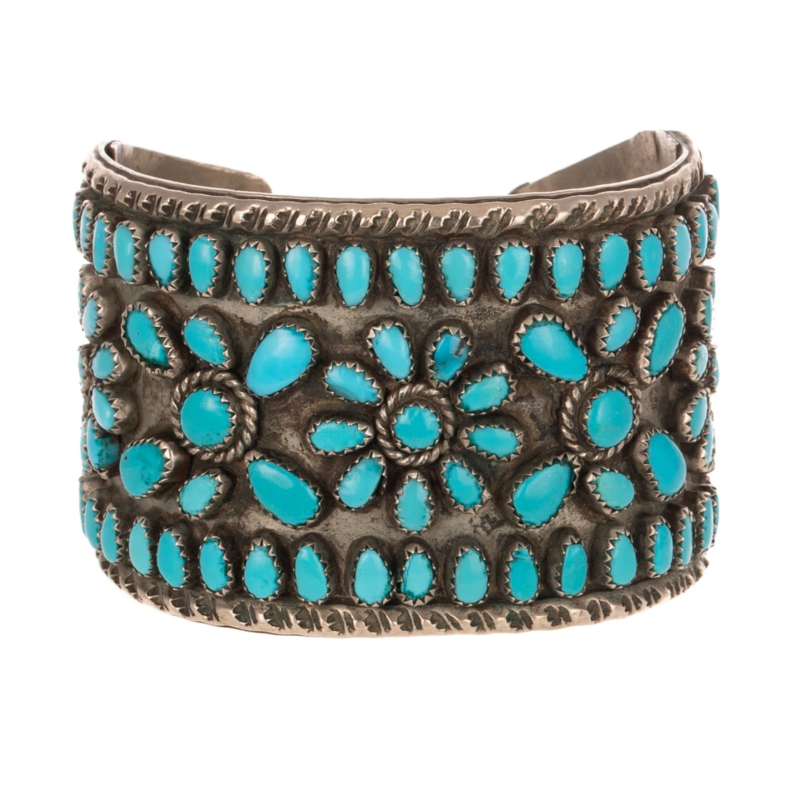 A Vintage Wide Zuni Turquoise Cuff Bracelet in Silver: Silver vintage cuff bracelet made by a Zuni artist featuring various shape well matched turquoise set in cluster floral design, 2 in. W, 2 1/2 interior Diam., 71.2 grams Provenance: From a private col