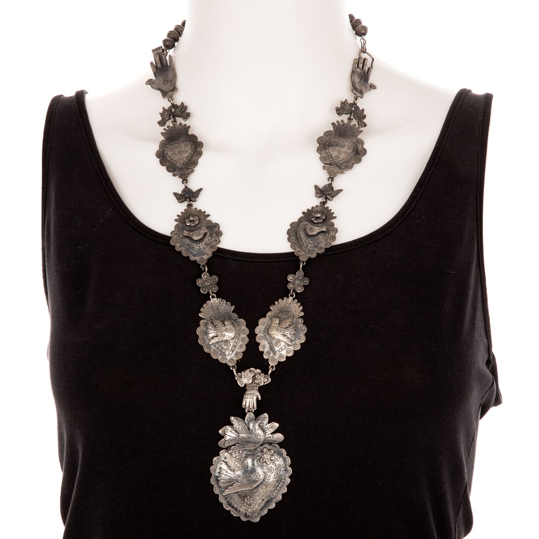 A Della & Francis James Navajo Necklace in Sterling Silver: Sterling silver necklace by Navajo artists Della and Francis James featuring dove, heart and hand links in squash blossom style, alternating with angels, doves, and rosettes, terminating in Navajo pea