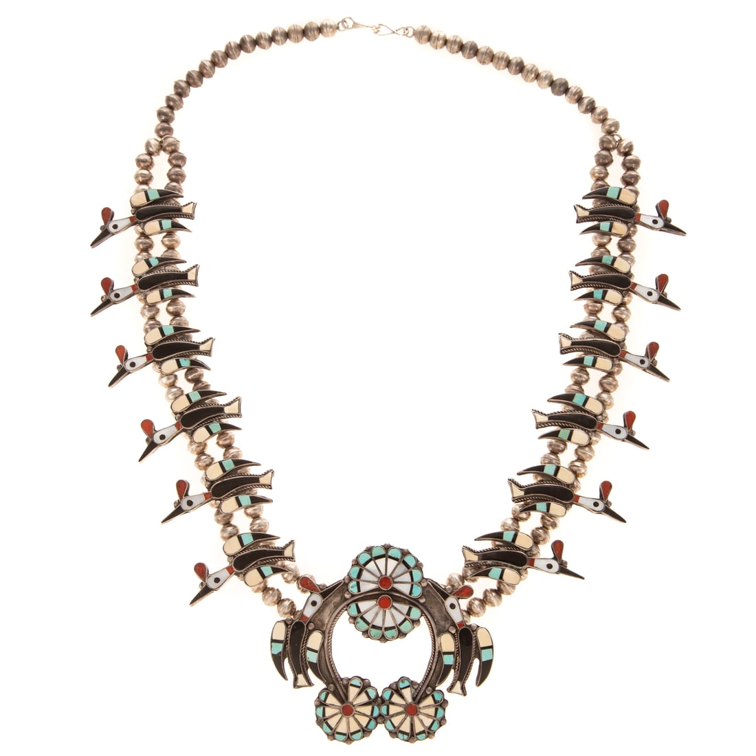 A Zuni Waterbird Squash Blossom by Vera Luna in Sterling Silver: c.1970s, Sterling silver waterbird squash blossom by Zuni designer Vera Luna (b. 1930), featuring mosaic inlaid gemstones in the twelve waterbirds surrounding a central floral and water bird Naja, sto
