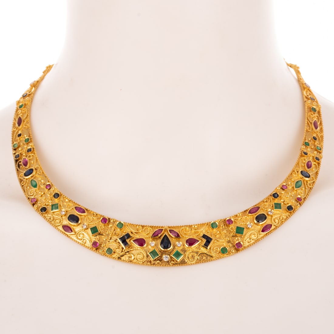 A Sapphire, Ruby & Emerald Necklace in 18K: 18K yellow gold necklace featuring articulated brushed gold panels with bezel and channel set mixed cut blue and pink sapphires, rubies, and emeralds with high polish bead details in various swirling 