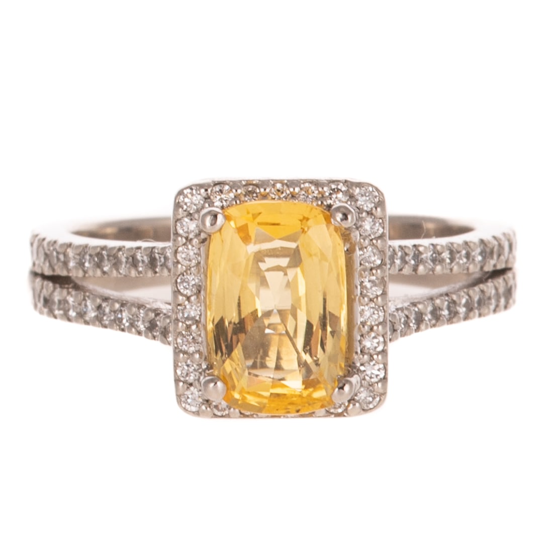 A Yellow Sapphire & Diamond Ring in Platinum: Platinum ring featuring a cushion cut yellow sapphire weighing approx. 2.50 ctw prong set in the center of a round diamond shared prong set halo with additional diamonds set on high polish split shank