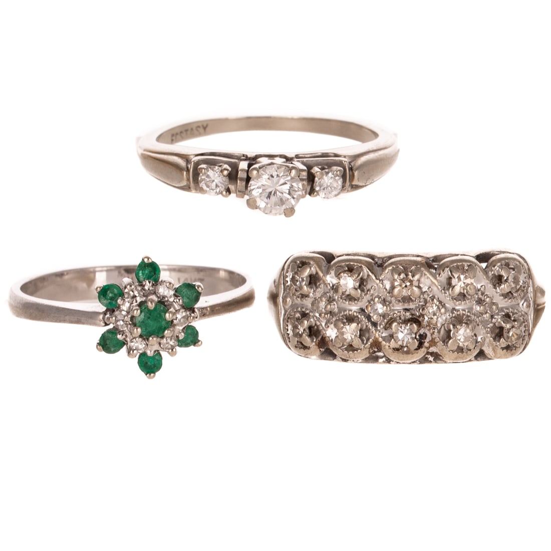 A Trio of Gemstone Rings in 14K: 1) 14K white gold ring featuring a round diamond weighing approx. 0.23 ct prong set, flanked by two round diamond side stone accents, sz 6, 2) 14K white gold flower ring featuring a round emerald pron