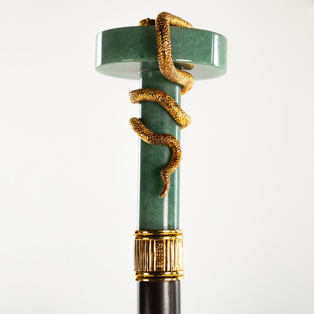 A Faberge Aventurine & Vermeil Serpent Cane: A Faberge cane with Aventurine handle, wooden shaft, sterling Vermeil snake and ruby accent. Marked "FABERGE" and "925." Includes blue velvet original fitted box, 36 3/4 in. L Provenance: From the