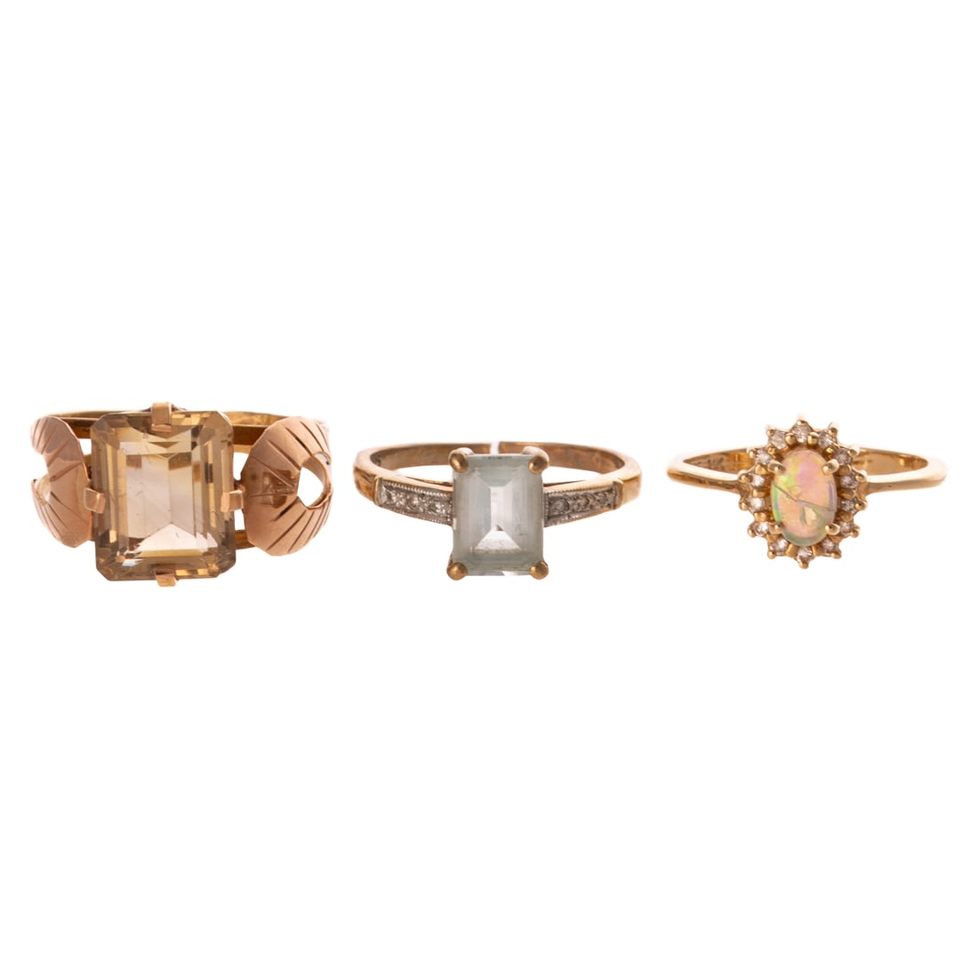 A Trio of Gemstone Rings in Gold: 1) 14K rose gold Egyptian ring featuring an emerald cut citrine measuring 11 x 9.1 mm, prong set, stylized leaf shoulders and split shank, sz 8.75, 2) 9K yellow gold ring with a step cut aquamarine,