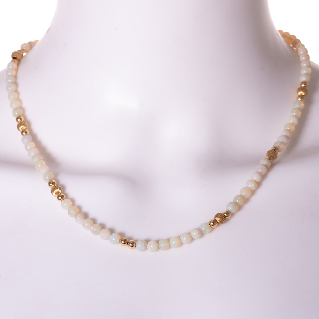 An Opal & Gold Bead Station Necklace in 14K: 14K yellow gold necklace featuring opal beads measuring 5 mm, evenly spaced between stations of gold fluted and high polish beads, filigree clasp, 19 1/4 in. L, 12..1 grams Provenance: From a private 