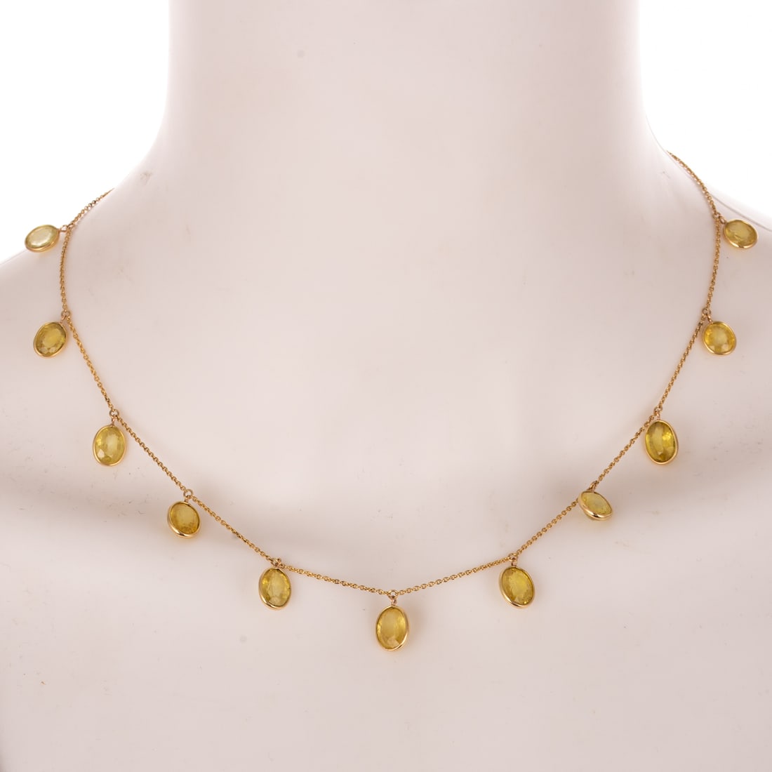 A Yellow Sapphire Dangle Necklace in 18K: 18K yellow gold necklace featuring evenly spaced dangling oval shaped yellow sapphires weighing approx. 21.00 carats bezel set, cable link chain with adjustable lengths at 16 1/4 in., 17 1/8 in., and 