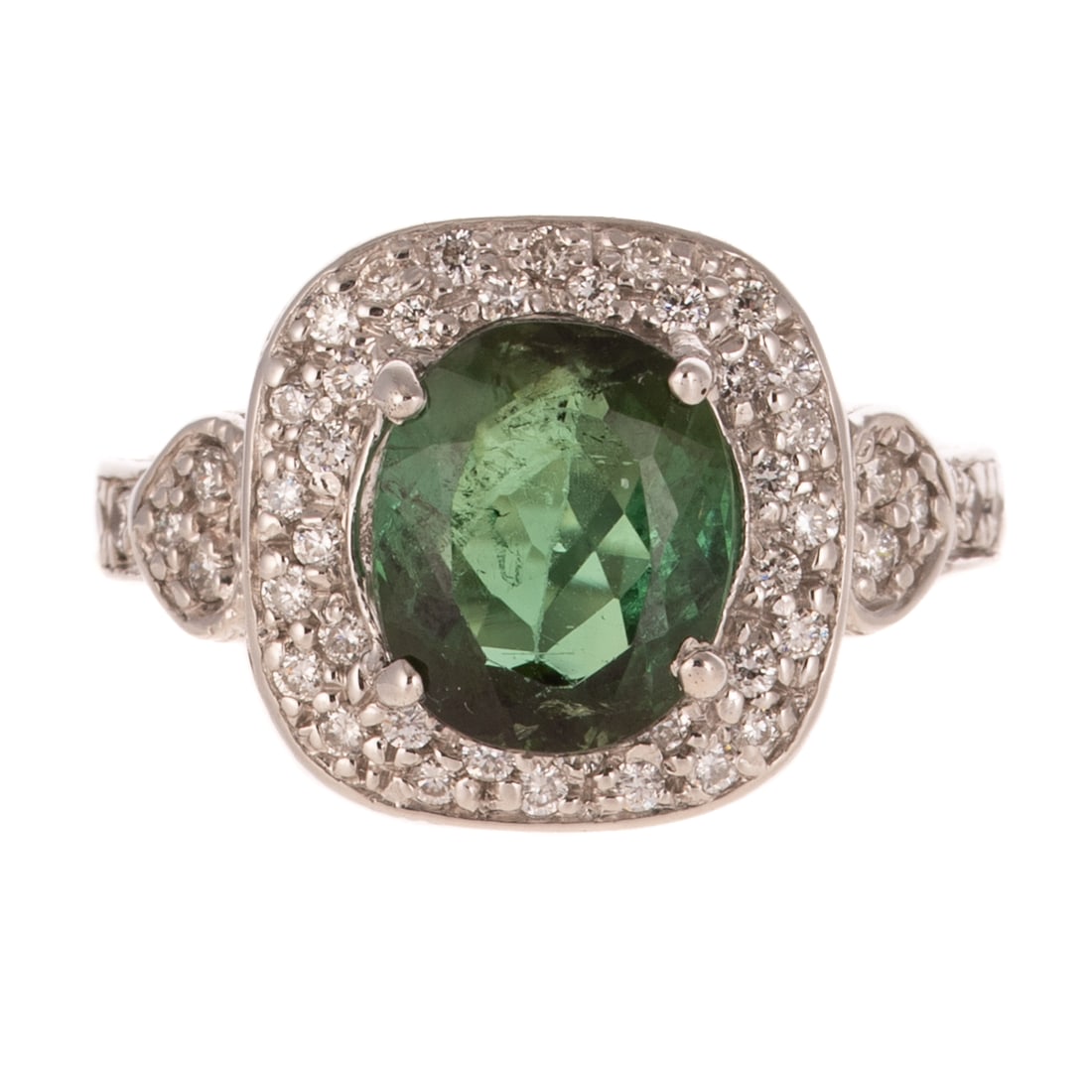 A Green Tourmaline & Diamond Ring in 18K: 18K white gold ring featuring a oval shaped green tourmaline weighing approx. 3.50 carats prong set in the center of a round diamond cluster bead set halo, decorative heart setting with round diamond 