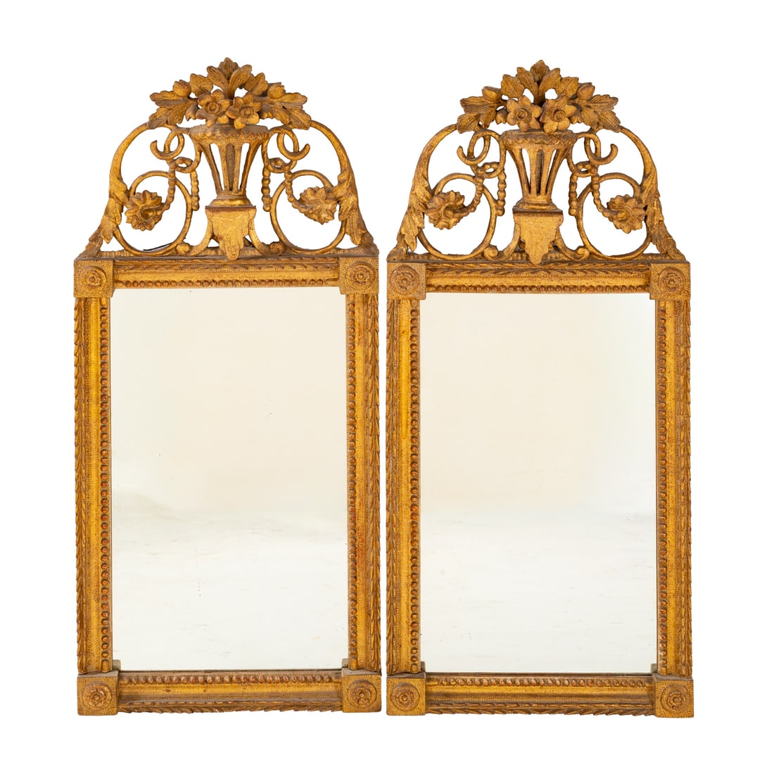 A Pair of Victorian Style Giltwood Mirrors: Carved floral and vase form crests over antiqued giltwood frames, each: 29 1/4 in. H, 13 1/2 in. W