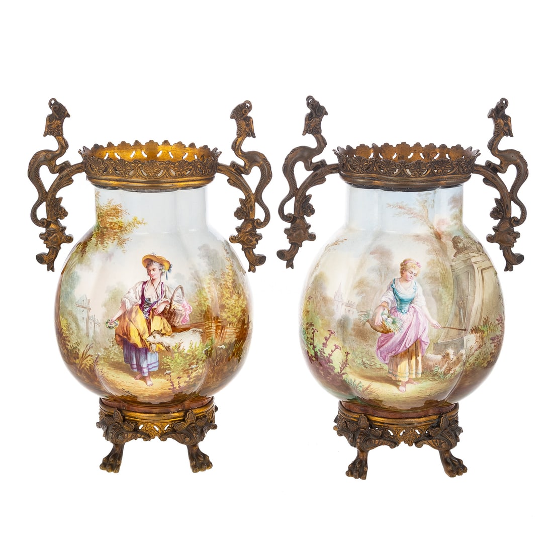 A Pair of Continental Mounted Vases: A pair of porcelain Continental metal mounted vases with dragon handles and paw feet, one depicting a woman holding a basket of eggs with two sheep at a fountain, and one depicting a woman holding a b