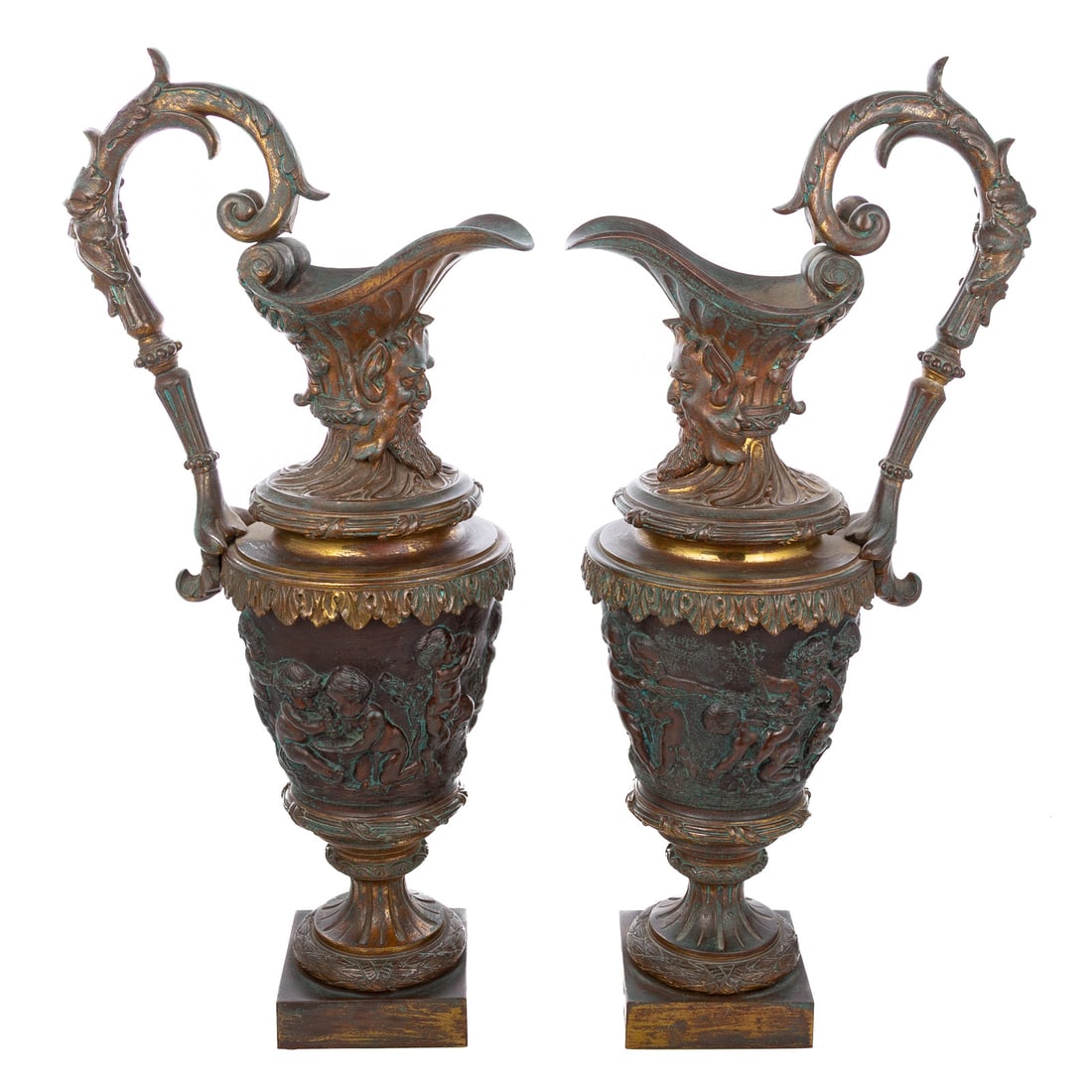 A Pair of Putti & Satyr Footed Ewers: 20th century, a pair of metal ewer-forms with scrolled foliate handle, raised relief putti decoration and satyr mask, 22 1/2 in. H, 6 3/4 in. Diam.