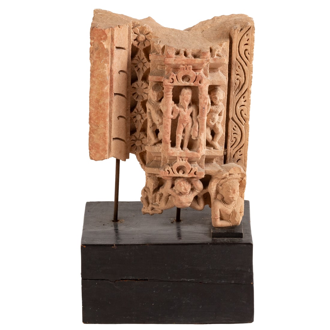 A Hindu Carved Stone Architectural Fragment: (India, possibly 15th/16th century) A carved red sandstone architectural fragment depicting Hindu divinities with rosette motifs and other decorative elements, on wooden base (can be removed from