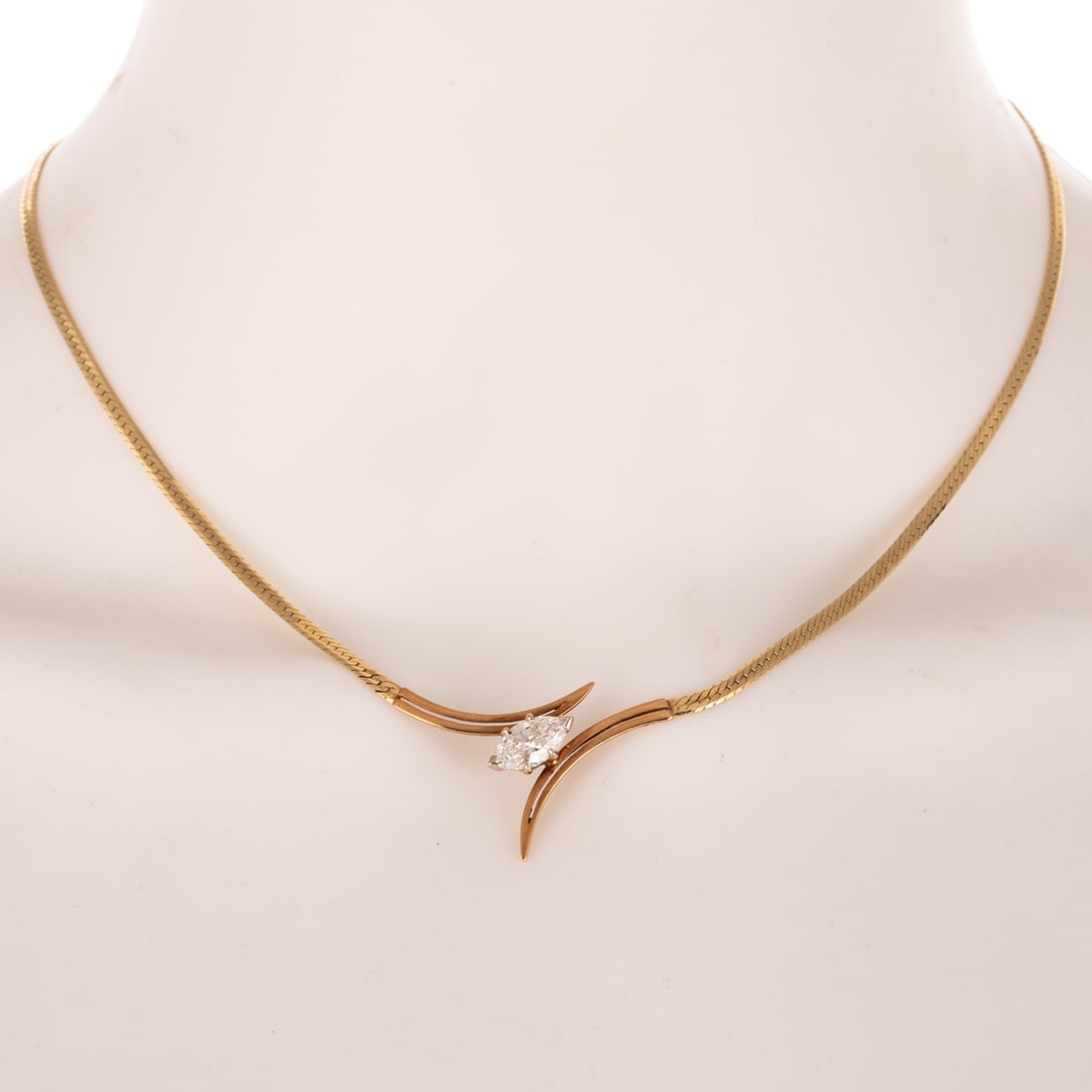 A 1.20 ct Diamond Bypass Necklace in 14K: 14K yellow gold bypass necklace featuring a marquise diamond weighing approx. 1.20 carats with an average color grade of F - G and an average clarity grade of VS, herringbone chain, box clasp with saf