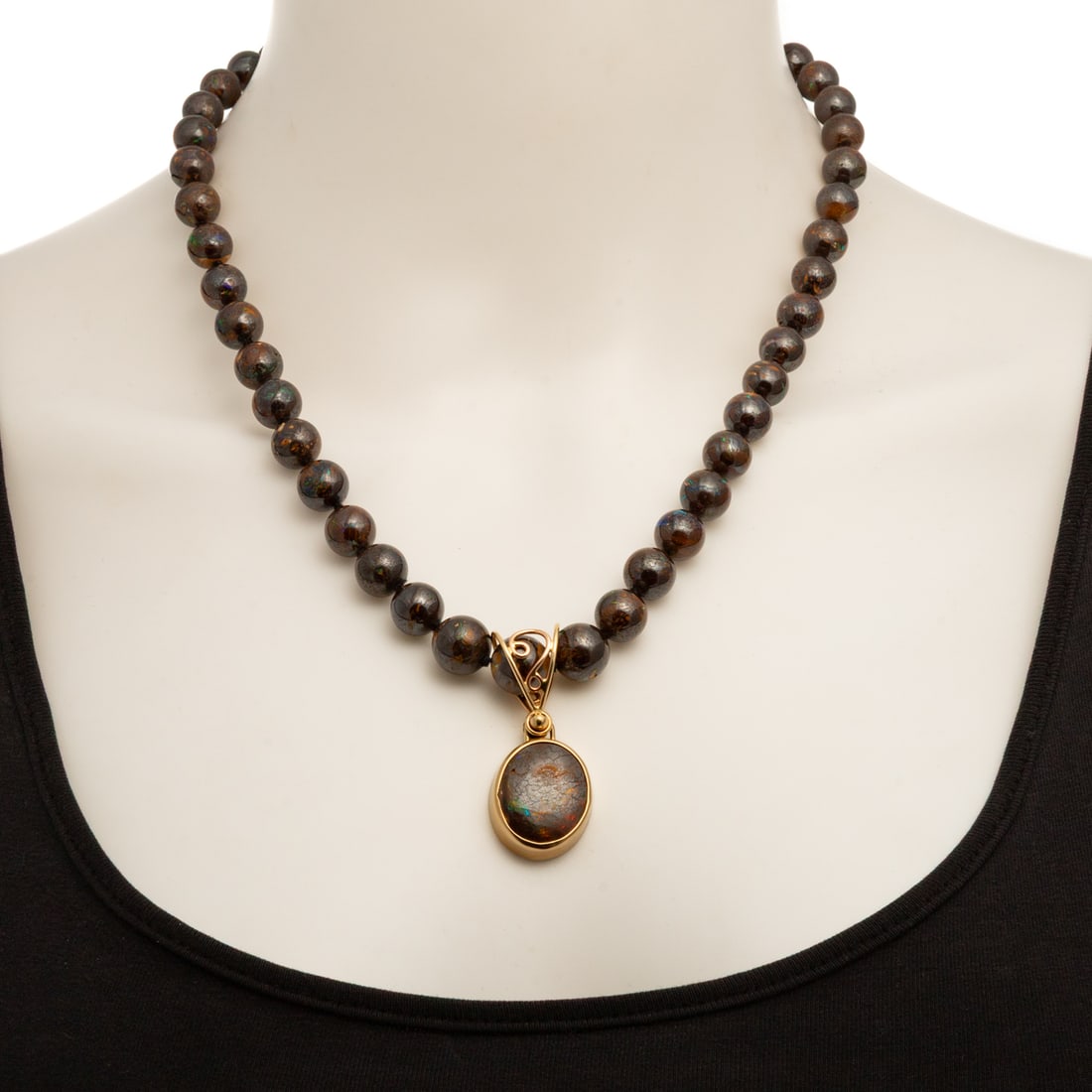 A Boulder Opal Pendant Necklace in 14K: 14K yellow gold boulder opal pendant necklace featuring slightly graduated boulder opal beads 8.6 - 11 mm with iridescent blue-green veining, suspending an oval cabochon boulder opal approx. 20 x 17 m