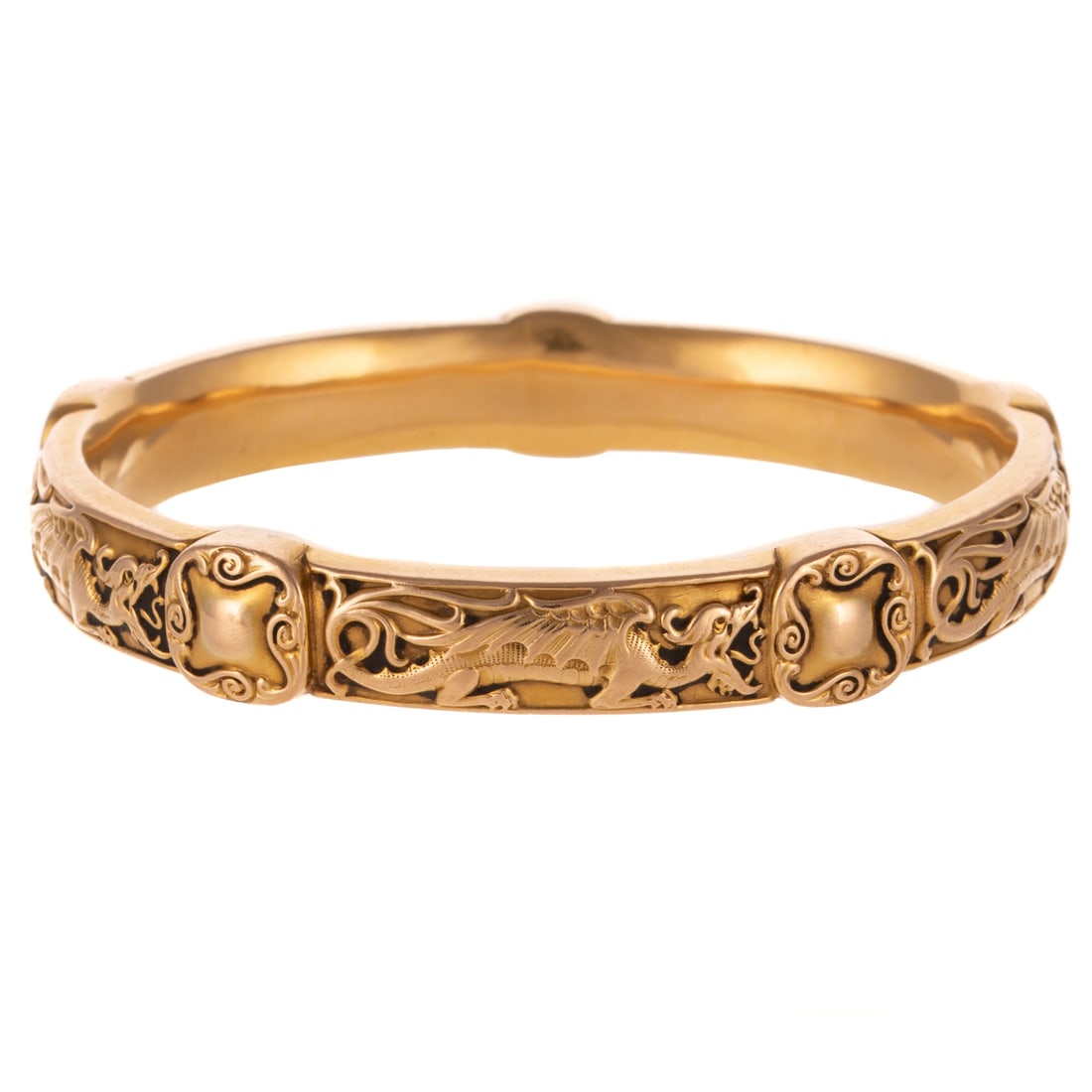 A Riker Brothers Art Nouveau Dragon Bangle in 14K: c.1890s, 14K yellow gold oval bangle bracelet by Riker Brothers, New York, designed with mythical dragons alternating with scrolling stations throughout entire bangle, 10.2 mm W, 2 5/8 in. interior