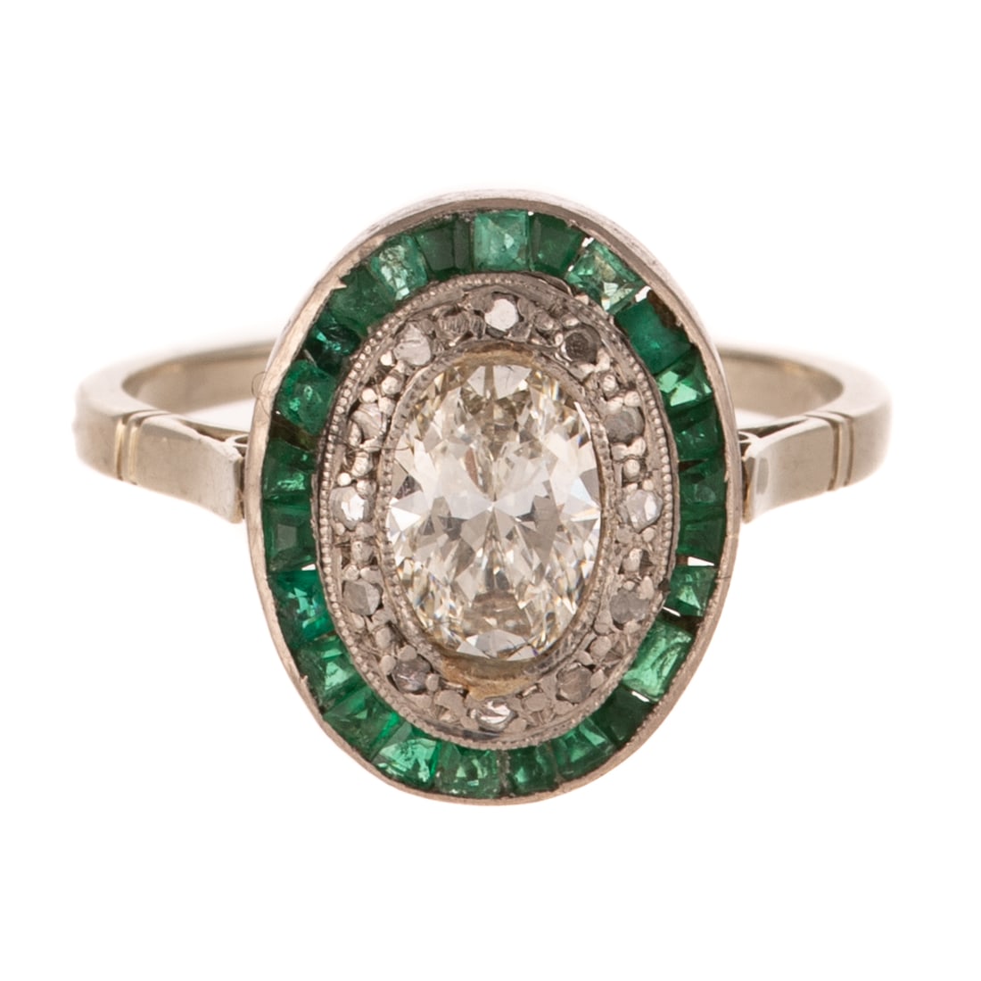 An Art Deco Diamond & Emerald Halo Ring in Platinum: c.1915s, platinum ring featuring an oval diamond weighing approx. 1.00 carats with an average color grade of J - K and an average clarity grade of VS set in center with milgrain accent, diamond and ch