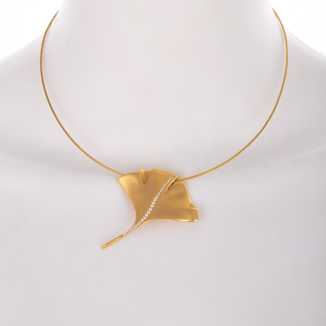 A Dan Peligrad Ginkgo Leaf Necklace in 18K: 18K yellow gold necklace by Dan Peligrad, New York, NY, featuring a large brushed finish Ginkgo leaf pendant with bead set diamonds down the center, hanging on a think braided 18K wire with pressure t