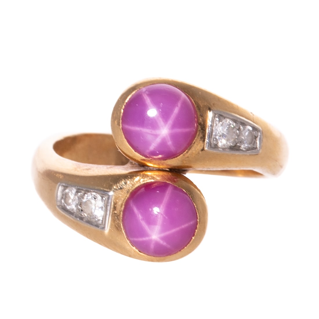 A Bypassing Star Ruby & Diamond Ring in 18K: 18K yellow gold ring featuring two bypassing round star ruby cabochons displaying six rayed stars bezel set with round diamonds prong set in platinum trailing behind, sz 7, 7.7 grams