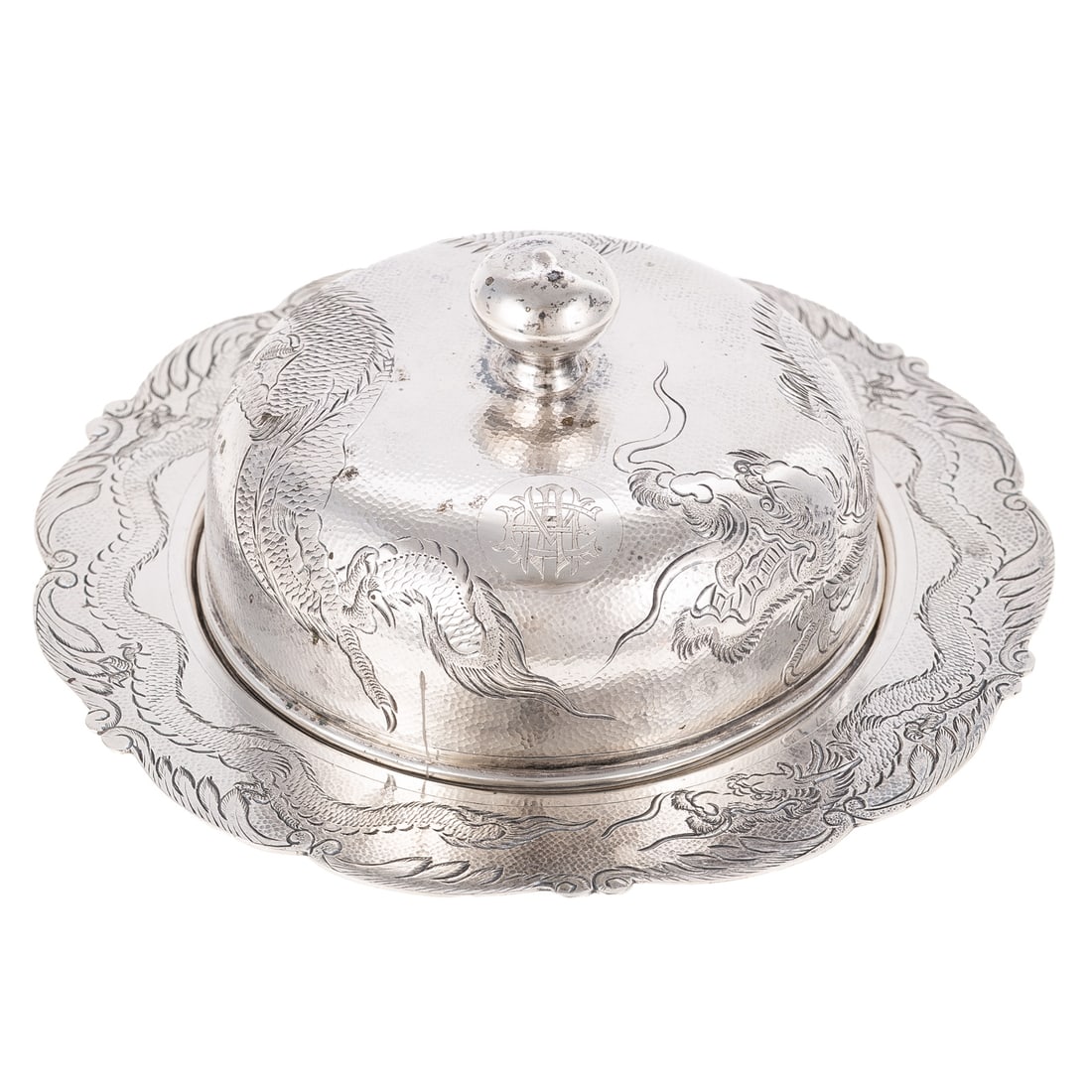 Chinese Export Silver Butter Dome: Early 20th century, maker's mark and "silver" stamped on the underside. Comprising a round undertray and dome, both with chased dragon decoration, against a hammered ground, monogrammed on the cover,