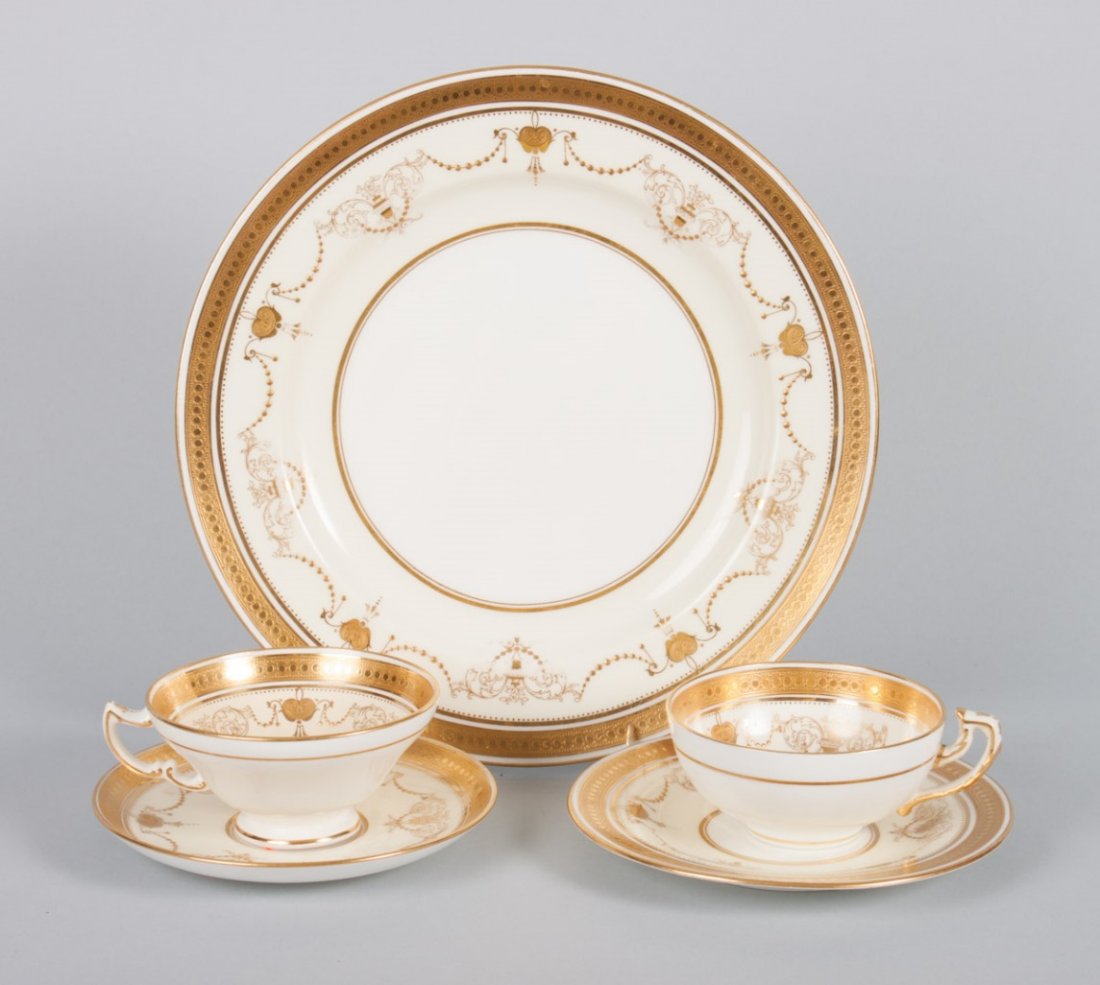 Minton china partial dinner service: first quarter-20th century; all with gilt, scroll, and urn decoration, comprising 48 pieces; 12 dinner plates, 8 bread plates, 19 saucers, 9 teacups, 4 bouillon cups, and 2 coffee cups