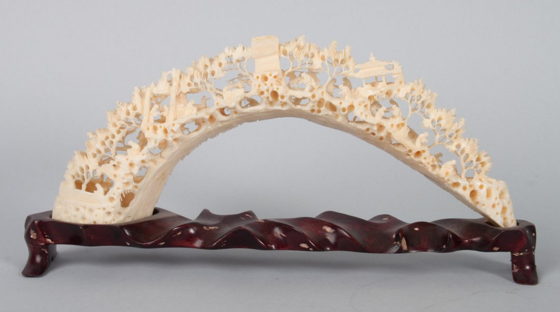 Chinese carved ivory village bridge: intricately carved miniature village among trees, with fitted wood stand, 4 in. H., 10 in. W. at base