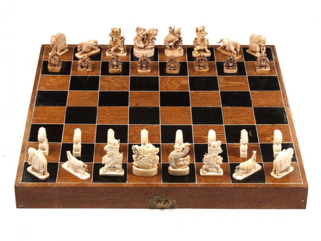 Chinese carved ivory chess set: 32 carved ivory chessmen, 16 stained brown, all with ink highlights carved to resemble fanciful beasts and animals, King figure - 2 1/2 in., board - 20 in. Sq.
