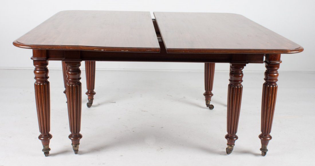 George IV mahogany banquet table: circa 1825; reeded legs ending in cup and roller casters, with overhanging top, 29 in. H., 58 in. L., 60 in. W., with five 17 in. extension leaves