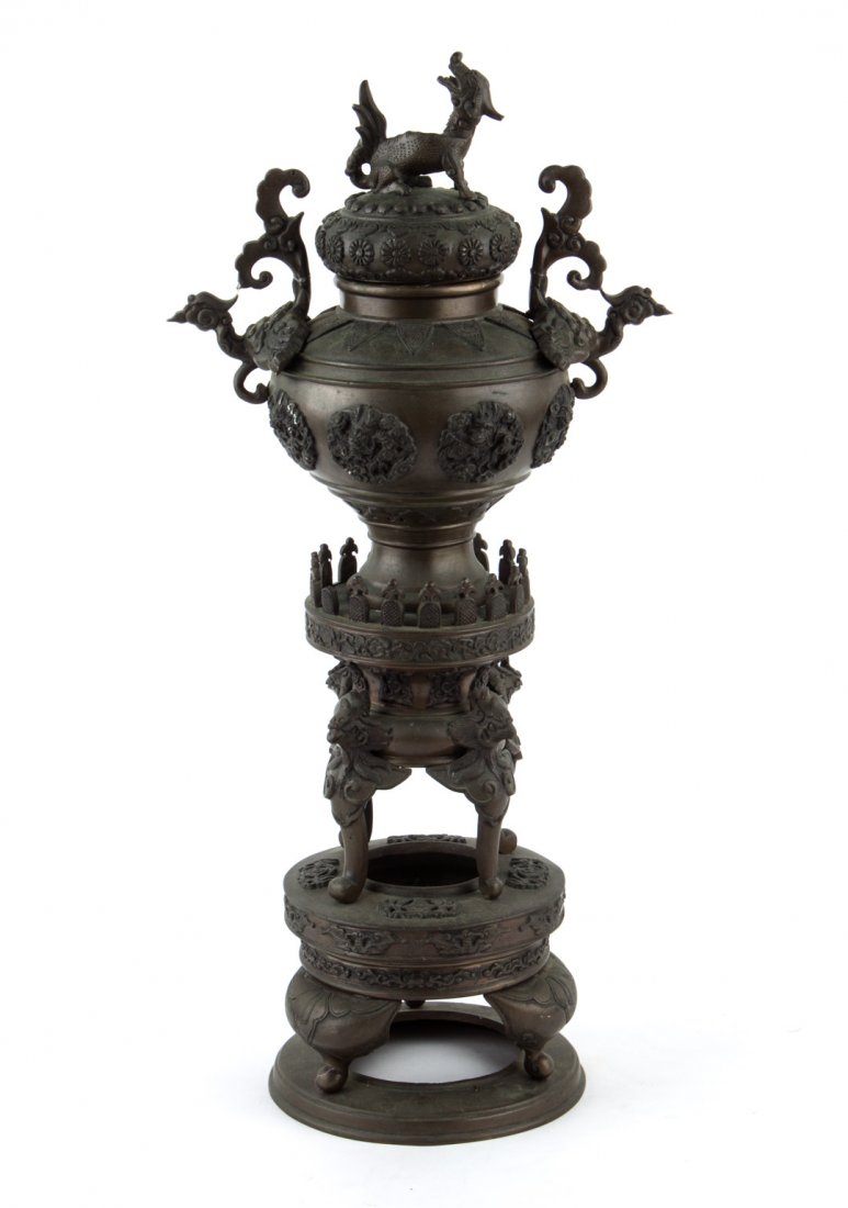Chinese Ming manner bronze vase on stand: vase with dragon finial, pair of phoenix-form handles, and relief floral rosettes, on stand with phoenix mask legs, and triform base, 21 in. H.