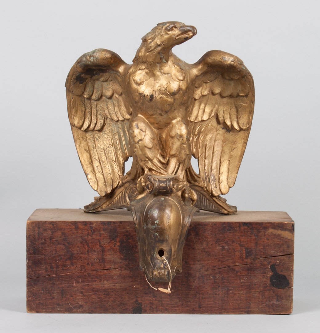 Cast iron eagle in the French Empire manner: late 19th century; gold-painted eagle modeled as bird standing on scroll, probably architectural piece, attached to wood block for display, 17 in. H., 16 in. W. for wood mount