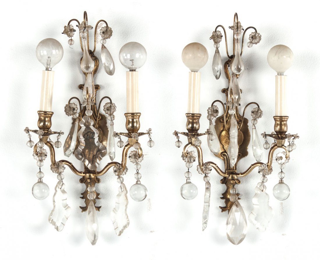 Pair of French brass wall sconces: 20th century; Rococo manner two-light wall sconces with crystal rosettes and prisms, 16 in. H., 9 in. W.