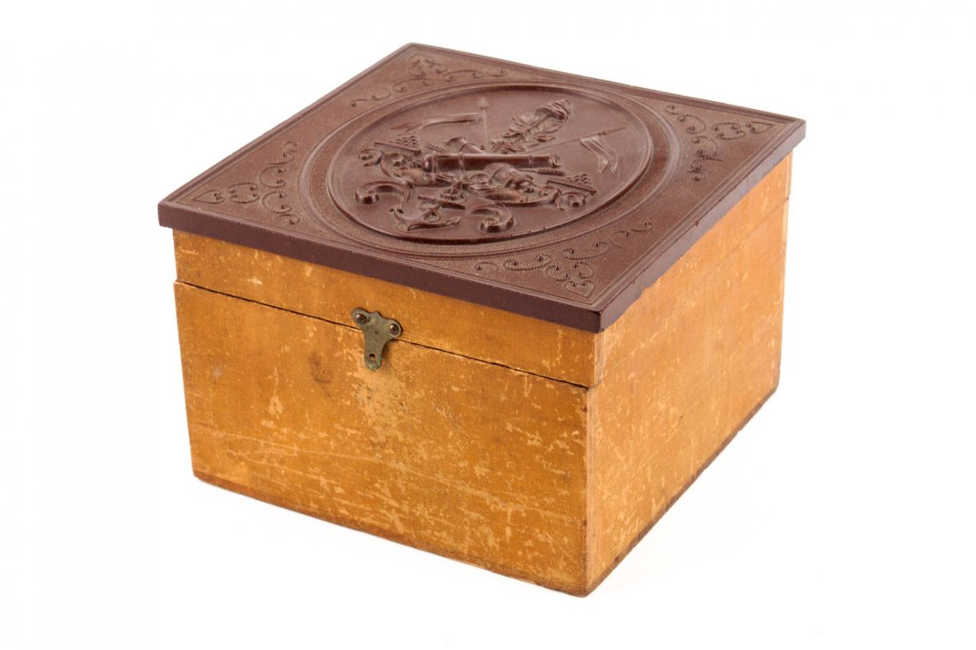 Trinket box with patriotic design on cover: Maple box with brown thermoplastic cover modelled with military trophies, the bottom impressed "Scovill Mfg. Co. NY," Civil War period, 4 5/8 in square section, 3 1/4 in. H.