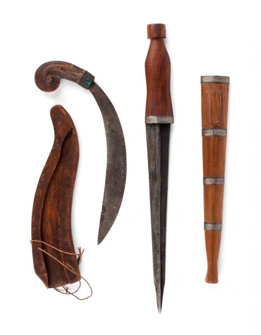 Two daggers from the Philippines: late 19th or early 20th century; one with curved blade and small fiddle-head handle, and with open-face wooden scabbard, 11 3/4 in. L. overall; the other with straight double-edged blade, the center r