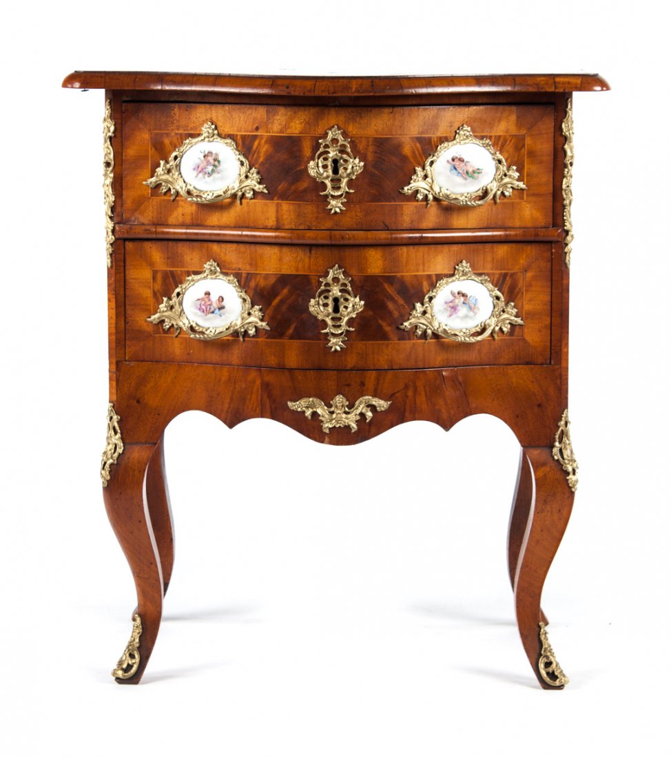 Louis XV style walnut commode: shaped front with two drawers, cast brass handles with painted porcelain medallions, escutcheons, chutes, and sabots, 29 in. H., 25 in. W., 19 in. D