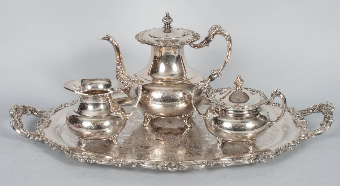 Silver-plated three-piece tea set and tray: comprising teapot, creamer and covered sugar, 9 in. H. of teapot; two-handled oval tray in. 24 1/2 in. L.